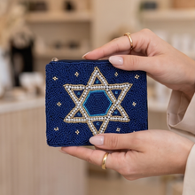 Load image into Gallery viewer, Navy blue hand-beaded Star of David pouch held in both hands, showcasing its detailed white, gold, and blue beadwork.