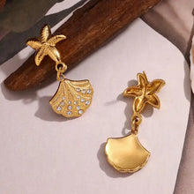 Load image into Gallery viewer, Gold earrings with starfish and shell designs on a neutral background