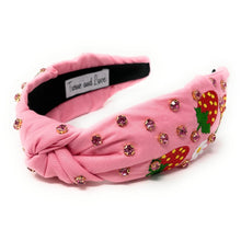 Load image into Gallery viewer, Smiling woman wearing a pink strawberry print headband with sparkling embellishments and matching strawberry statement earrings outdoors.