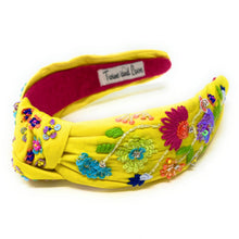 Load image into Gallery viewer, Close-up of a woman accessorized with a floral embroidered headband and colorful parrot statement earrings in natural sunlight.