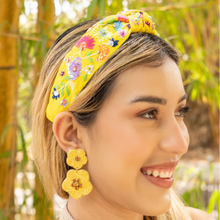 Load image into Gallery viewer, Woman wearing a bright yellow embroidered headband with colorful floral details and vibrant parrot statement earrings outdoor