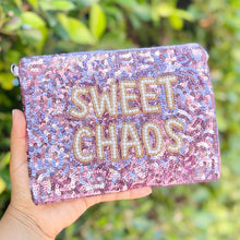 Load image into Gallery viewer, Sequined pouch with 'Sweet Chaos' text held by a hand against a green leafy background