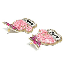 Load image into Gallery viewer, Statement earrings shaped like pink winter mittens, decorated with pearls, seed beads, rhinestones, and embroidered “Hope” text.