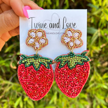 Load image into Gallery viewer, Smiling woman wearing a pink strawberry print headband with sparkling embellishments and matching strawberry statement earrings outdoors.