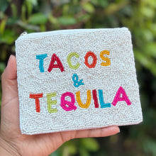 Load image into Gallery viewer, Hand holding a pouch with 'TACOS &amp; TEQUILA' text against a blurred green background