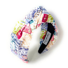 Load image into Gallery viewer, Vacation-themed knotted headband decorated with airplane icons and passport-style stamps in bright colors.