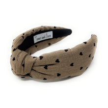 Load image into Gallery viewer, Tan headband with black heart patterns on a white background