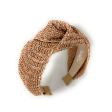 Load image into Gallery viewer, A woven natural fiber headband in a light tan color, featuring a knotted bow detail on top and adjustable plastic snap fasteners on the back, shown on a plain white background.