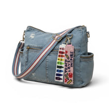 Load image into Gallery viewer, Denim handbag with colorful strap and text tag on a white background