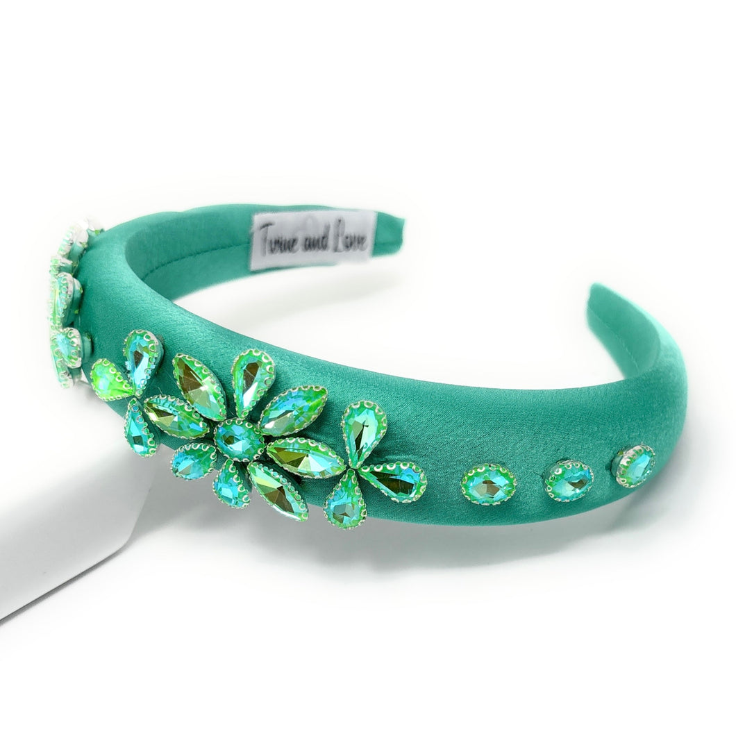Teal headband with decorative flowers on a white background