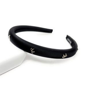 Black headband with small silver bow decorative charms on a white background