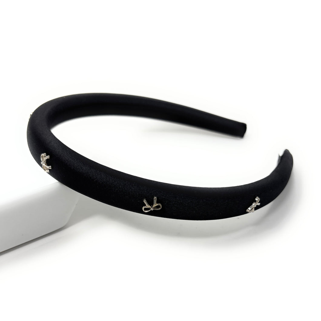 Black headband with small bows decorative charms on a white background