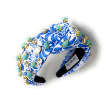 Load image into Gallery viewer, A blue and white floral-patterned headband adorned with turquoise stones and sparkling gems. It conveys a vibrant, elegant, and artistic flair.