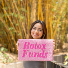 Load image into Gallery viewer, A vibrant pink 'Botox Funds' sign held by a woman against a backdrop of bamboo.