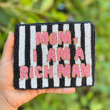 Load image into Gallery viewer, A hand holds a small rectangular beaded pouch with black and white stripes and pink text that reads 'MOM, I AM A RICH MAN' against a blurred green outdoor background.