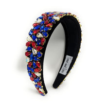 Load image into Gallery viewer, A wide, black headband adorned with vibrant red, blue, and clear gemstones arranged in clusters. The design conveys elegance and boldness.