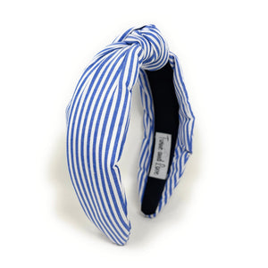 Blue and white striped headband with a knotted detail in the center, set against a plain white background, conveying a trendy, nautical style.