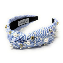 Load image into Gallery viewer, A blue and white striped headband adorned with pearls and gold beads. It features a knot design, creating an elegant and stylish accessory.