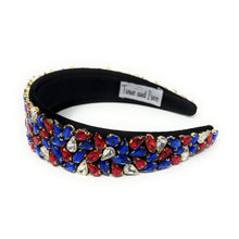 Load image into Gallery viewer, A wide, black headband adorned with vibrant red, blue, and clear gemstones arranged in clusters. The design conveys elegance and boldness.