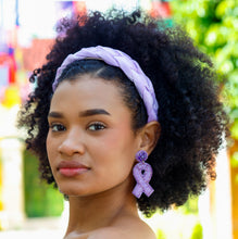 Load image into Gallery viewer, Model wearing a lavender braided headband and purple awareness ribbon earrings with a black ruffled dress in an outdoor setting.