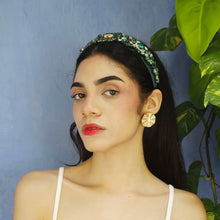 Load image into Gallery viewer, A stylish young woman posing with a green headband and statement earrings against a blue wall.