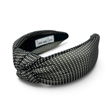 Load image into Gallery viewer, A wide fabric headband with a knotted front, featuring a black and white polka dot pattern. A small white label inside reads 'Towel and Lace'.