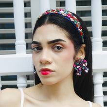 Load image into Gallery viewer, A model displaying vibrant jewelry, including a bow-shaped earring and a decorative headband.