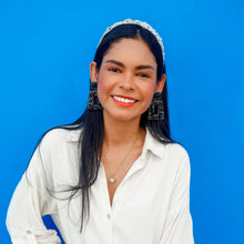 Load image into Gallery viewer, Woman showcasing stylish black earrings with a white shirt and blue backdrop.