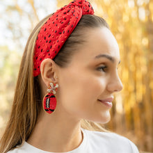 Load image into Gallery viewer, Woman wearing a red headband and colorful earrings in a natural setting.