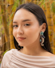 Load image into Gallery viewer, Model wearing colorful Blue Seahorse earrings in a natural setting.