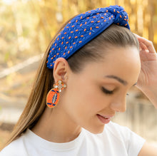 Load image into Gallery viewer, A woman wearing a stylish blue headband with colorful accents and large earrings, showcasing a chic look.