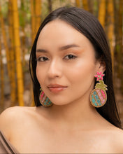 Load image into Gallery viewer, Model showcasing colorful pineapple earrings in a natural setting.