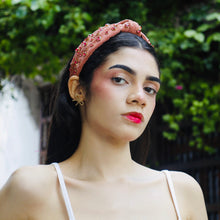 Load image into Gallery viewer, Stylish female model showcasing a pink headband and golden earrings in a lush outdoor setting.