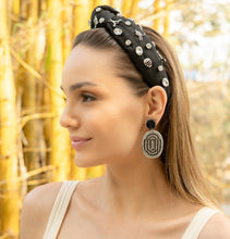 Load image into Gallery viewer, A model showcasing an elegant black hockey headband adorned with jewels and stylish earrings in a natural setting.