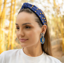 Load image into Gallery viewer, woman wearing a blue headband with pearls and elegant earrings in a natural setting