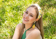 Load image into Gallery viewer, Elegant lemon earrings complementing a woman's outfit in a vibrant green background.