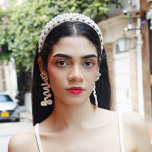 Load image into Gallery viewer, Close-up of a trendy model showcasing elegant earrings and a pearl headband in a chic outdoor setting.