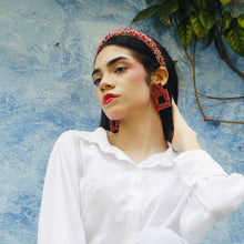 Load image into Gallery viewer, An elegant woman posing with a white shirt and vibrant red accessories in front of a blue wall.