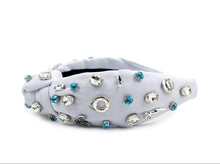 Load image into Gallery viewer, White headband adorned with sparkling rhinestones, swimming charms and blue gems, radiating elegance. The fabric is softly pleated, creating a textured, luxurious look.