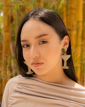 Load image into Gallery viewer, A model showcasing unique cocktail-themed earrings in a natural setting.
