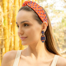Load image into Gallery viewer, Close-up of a woman wearing trendy orange accessories, including a headband and earrings, surrounded by natural bamboo.