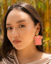 Load image into Gallery viewer, Close-up of a model wearing unique pink t-shirt earrings in a natural setting.
