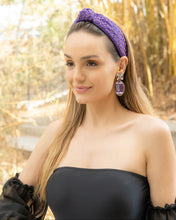 Load image into Gallery viewer,  A woman wearing a purple headband and statement earrings in a natural setting.
