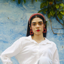 Load image into Gallery viewer, Statement red earrings complementing a chic white shirt and blue background.