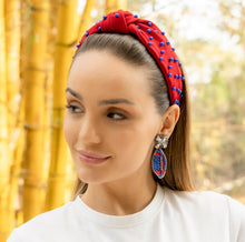 Load image into Gallery viewer, Fashionable woman showcasing a stylish red headband and elaborate earrings in a natural setting.