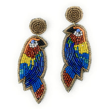 Load image into Gallery viewer, Close-up of a woman accessorized with a floral embroidered headband and colorful parrot statement earrings in natural sunlight.