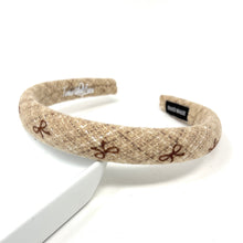 Load image into Gallery viewer,  A stylish beige headband with a textured design and brown bows.