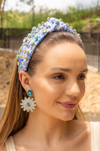 Load image into Gallery viewer, A woman wearing a vibrant green headband with floral embellishments and colorful statement
