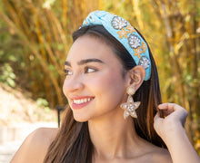 Load image into Gallery viewer, Stylish woman posing with a blue headband and star earrings in a lush bamboo setting.
