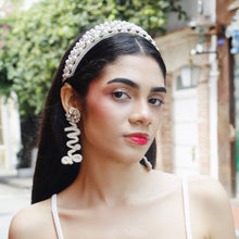 Load image into Gallery viewer, A stylish model posing in a white crop top with a pearl headband and statement earrings.